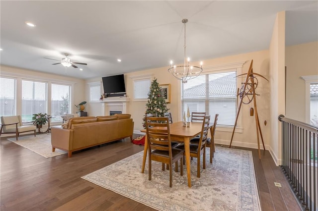 dining area featuring ceiling fan with notable chandelier and dark wood-type flooring