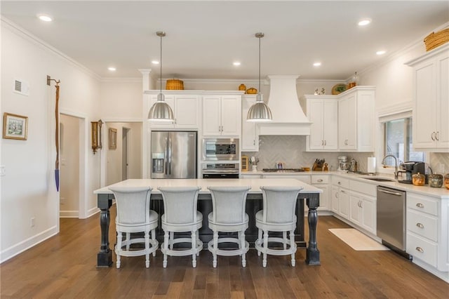 kitchen with white cabinetry, stainless steel appliances, pendant lighting, a kitchen island, and custom range hood