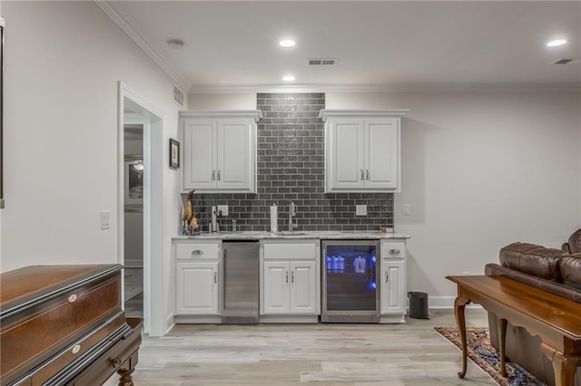 bar with backsplash, white cabinets, and beverage cooler