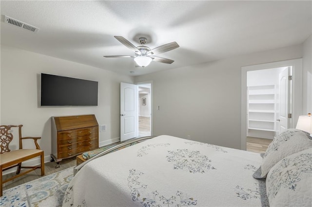 bedroom with a closet, a spacious closet, ceiling fan, and light hardwood / wood-style flooring