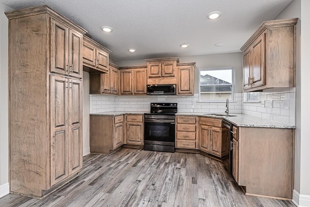 kitchen featuring light stone countertops, tasteful backsplash, sink, electric range, and hardwood / wood-style flooring