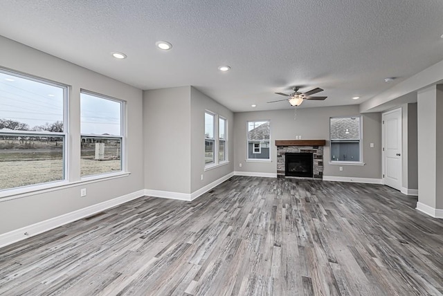 unfurnished living room with hardwood / wood-style flooring, plenty of natural light, a fireplace, and a textured ceiling