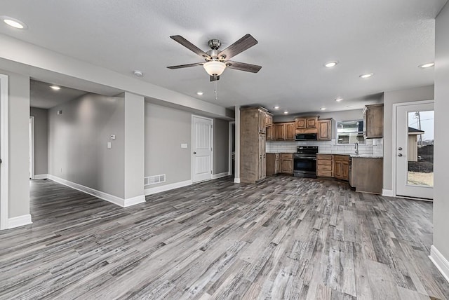 unfurnished living room featuring ceiling fan, light hardwood / wood-style floors, and sink