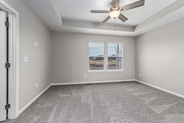 spare room featuring carpet flooring, ceiling fan, and a tray ceiling