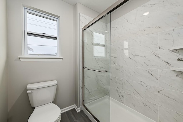 bathroom featuring toilet and a shower with door