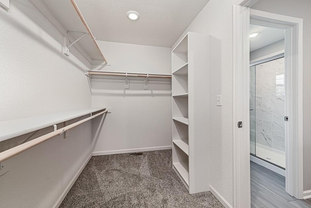 spacious closet featuring dark colored carpet