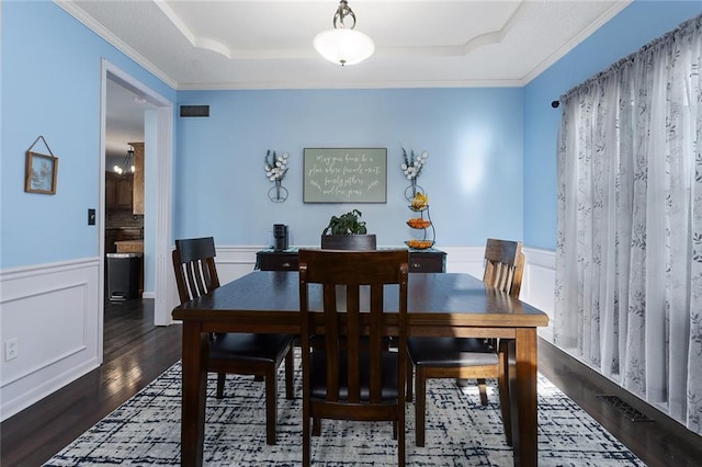 dining space featuring dark hardwood / wood-style floors, a tray ceiling, and crown molding