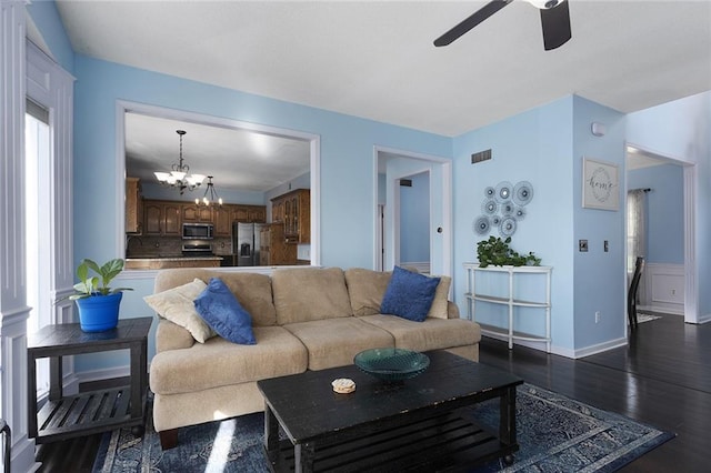 living room featuring ceiling fan with notable chandelier and dark hardwood / wood-style flooring