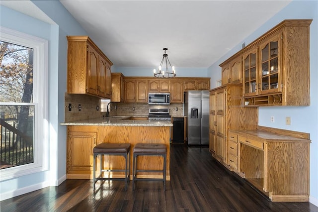 kitchen featuring kitchen peninsula, appliances with stainless steel finishes, tasteful backsplash, sink, and dark hardwood / wood-style floors