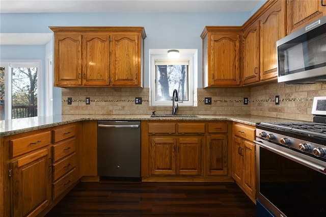 kitchen with sink, tasteful backsplash, light stone counters, dark hardwood / wood-style flooring, and appliances with stainless steel finishes