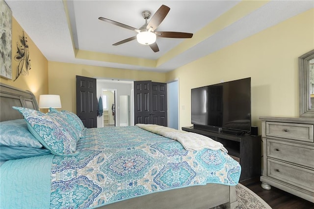 bedroom featuring dark hardwood / wood-style floors, a raised ceiling, and ceiling fan