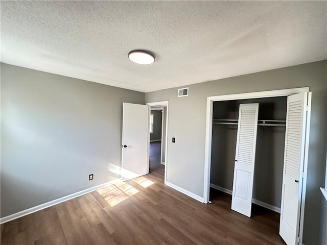 unfurnished bedroom with a closet, dark wood-type flooring, and a textured ceiling