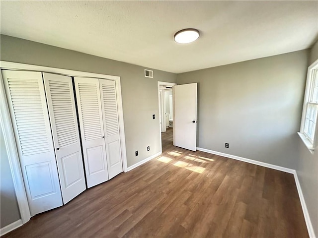 unfurnished bedroom featuring dark hardwood / wood-style flooring and a closet