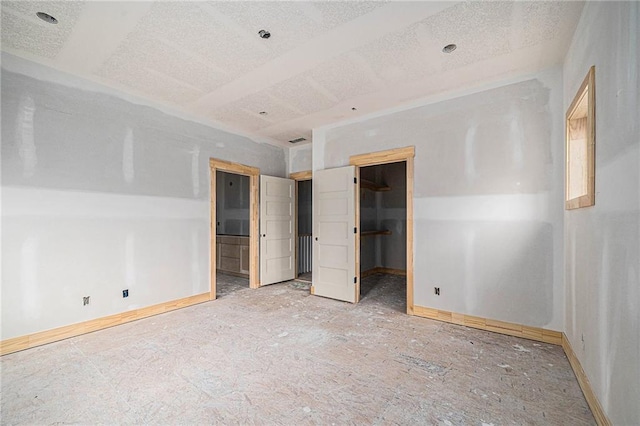 unfurnished bedroom with a textured ceiling, vaulted ceiling, ensuite bathroom, and a spacious closet