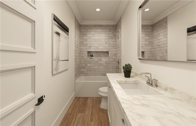 full bathroom with ornamental molding, tiled shower / bath combo, vanity, wood-type flooring, and toilet