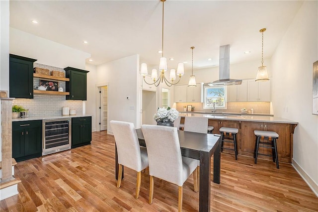 dining area featuring wine cooler, recessed lighting, an inviting chandelier, and light wood-style flooring