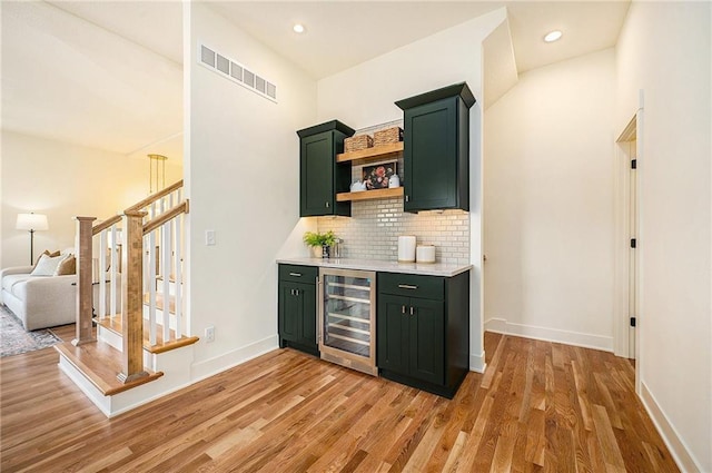 bar with wine cooler, visible vents, backsplash, and light wood-style floors