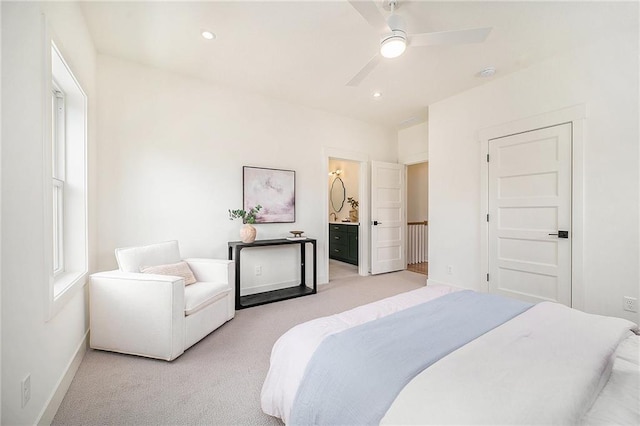 bedroom featuring baseboards, a ceiling fan, ensuite bath, and light colored carpet