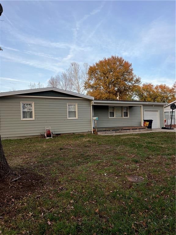 rear view of property featuring a garage and a yard