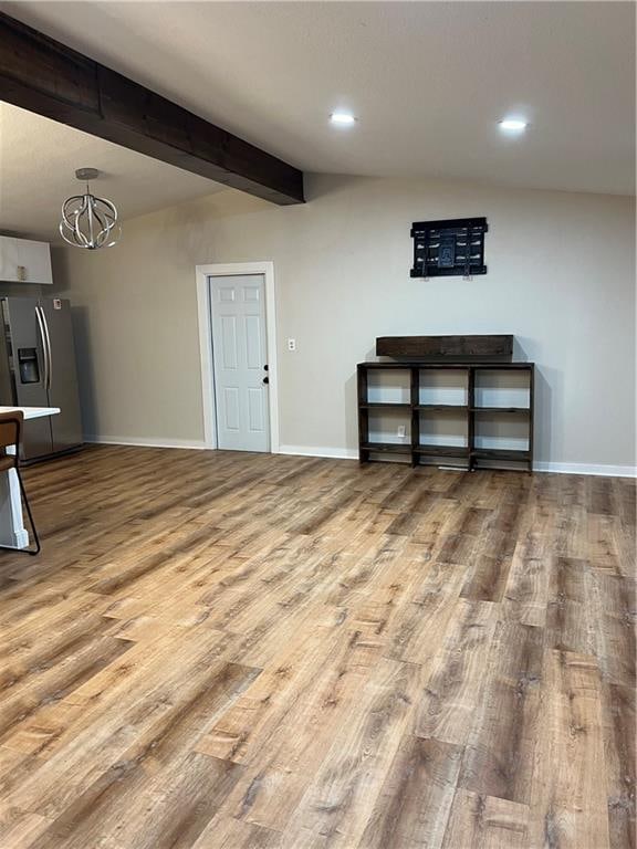 unfurnished living room with beam ceiling, hardwood / wood-style floors, and a notable chandelier