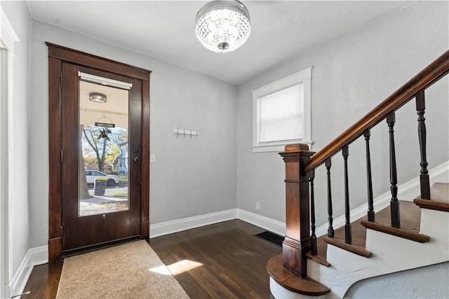 entryway featuring dark wood-type flooring and an inviting chandelier