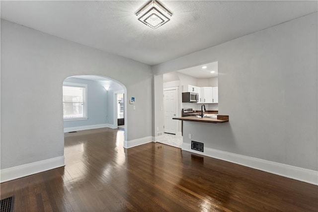 unfurnished living room with sink and dark hardwood / wood-style floors