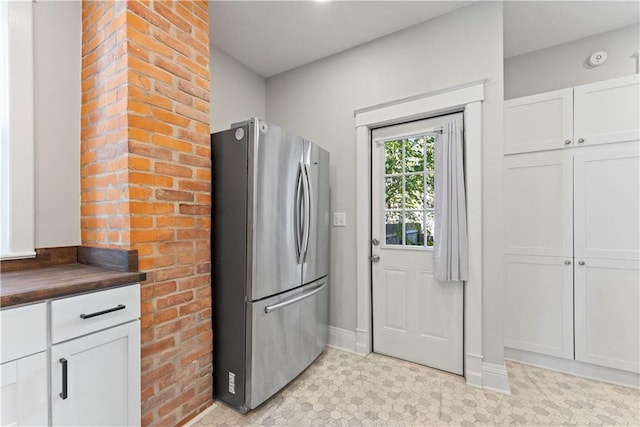 kitchen featuring wood counters, white cabinetry, and stainless steel refrigerator