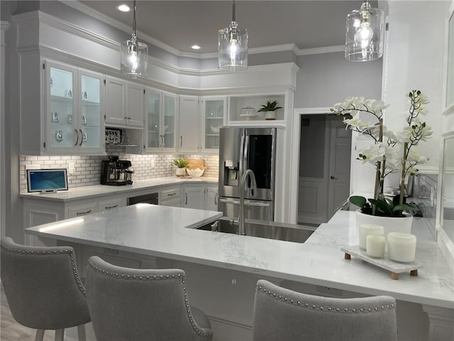 kitchen featuring crown molding, stainless steel fridge with ice dispenser, a breakfast bar, and pendant lighting