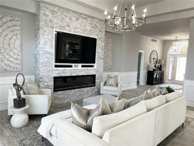 living room with a fireplace, wood-type flooring, and an inviting chandelier