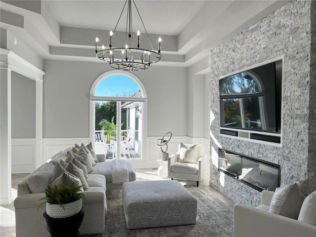 living room featuring a fireplace, a high ceiling, a chandelier, and a tray ceiling