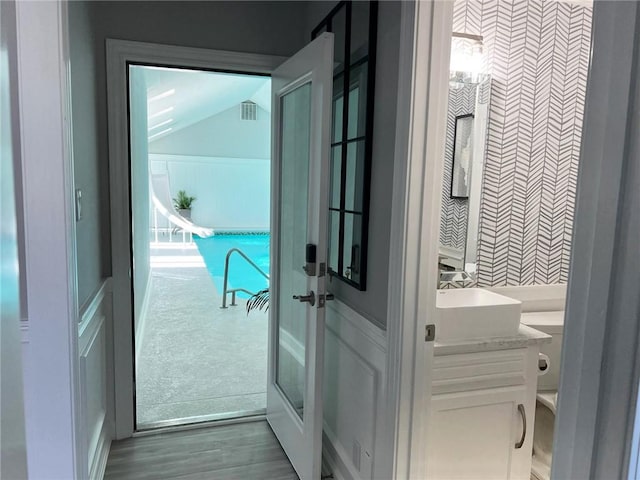 doorway with hardwood / wood-style floors, sink, and vaulted ceiling