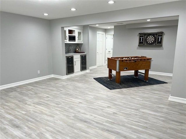 rec room featuring wine cooler, light hardwood / wood-style flooring, and wet bar