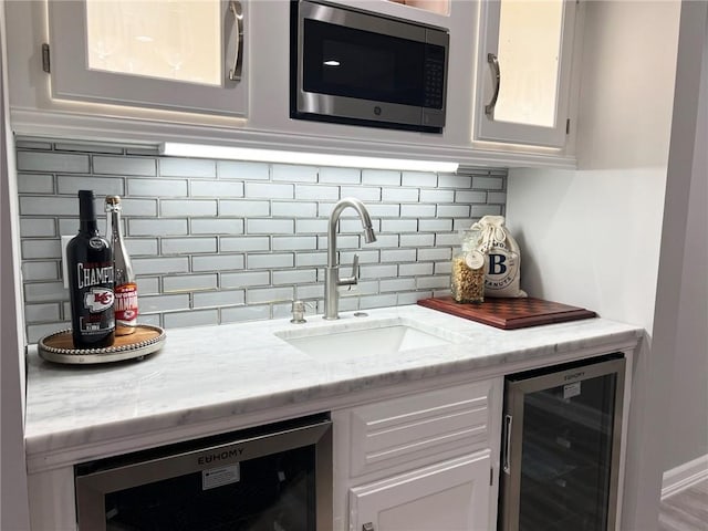 kitchen featuring stainless steel microwave, white cabinetry, and beverage cooler