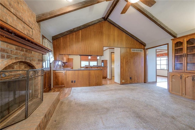 unfurnished living room featuring beamed ceiling, light colored carpet, high vaulted ceiling, and a wealth of natural light