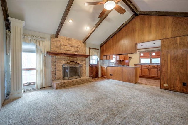 unfurnished living room featuring beamed ceiling, a fireplace, a healthy amount of sunlight, and wood walls