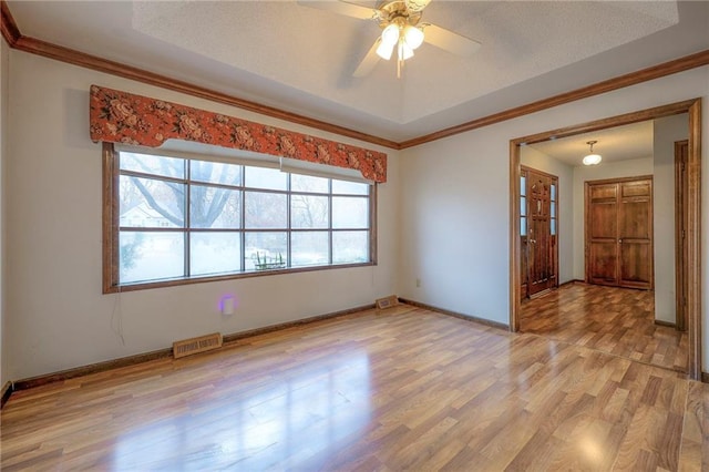 spare room with a textured ceiling, light wood-type flooring, ceiling fan, and crown molding