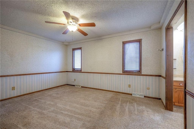 carpeted empty room with ceiling fan and a textured ceiling