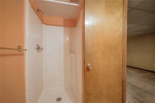 bathroom with a paneled ceiling and a shower