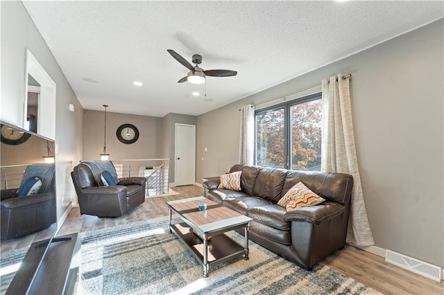 living room featuring a textured ceiling, light hardwood / wood-style floors, and ceiling fan