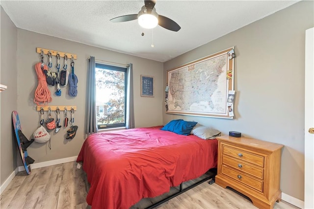 bedroom featuring ceiling fan, a textured ceiling, and light wood-type flooring