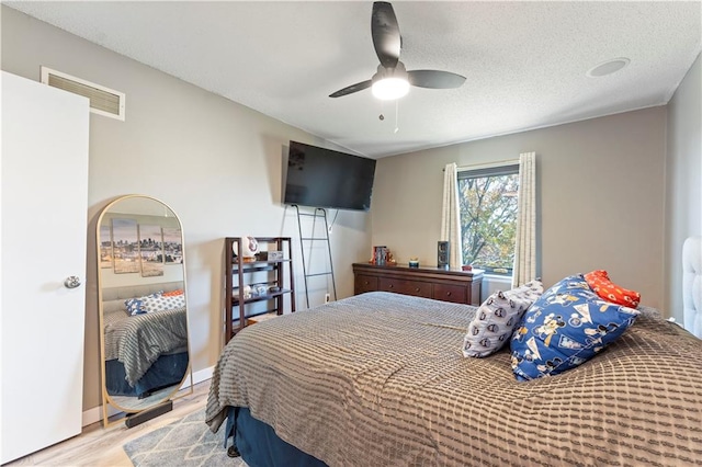 bedroom with ceiling fan, a textured ceiling, and light hardwood / wood-style flooring