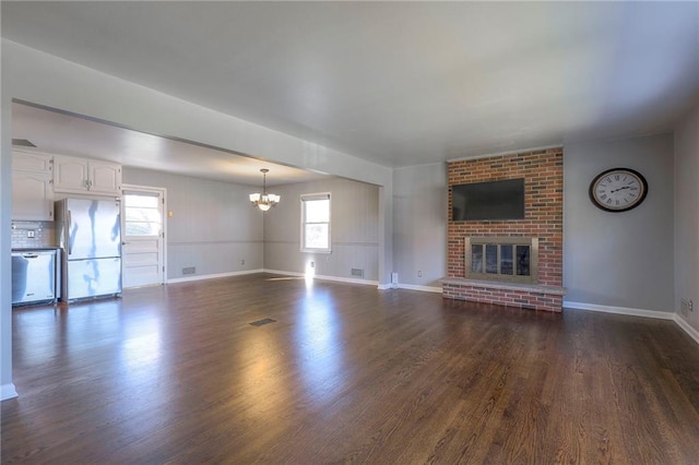 unfurnished living room with a fireplace, a wealth of natural light, and dark wood-type flooring