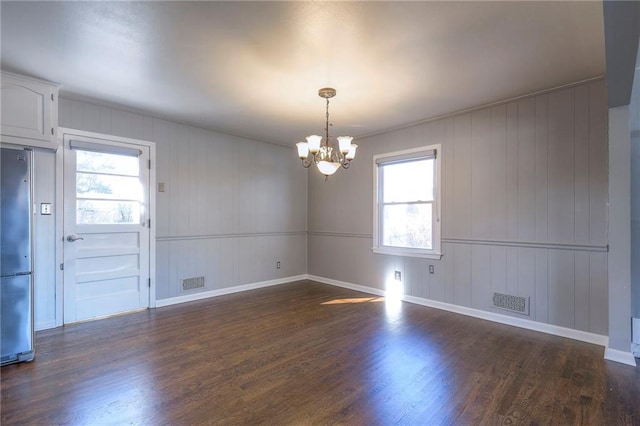 empty room with plenty of natural light, a chandelier, and dark hardwood / wood-style floors