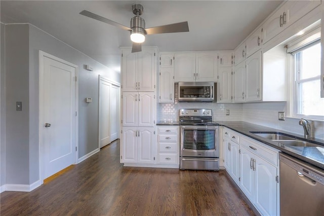 kitchen with sink, dark wood-type flooring, tasteful backsplash, white cabinets, and appliances with stainless steel finishes