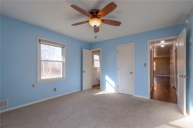 unfurnished bedroom with carpet, ensuite bathroom, and ceiling fan