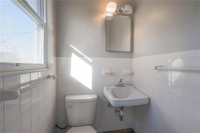 bathroom with toilet, tile walls, and sink