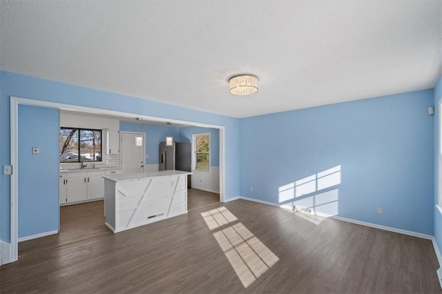 unfurnished living room featuring sink and dark hardwood / wood-style floors