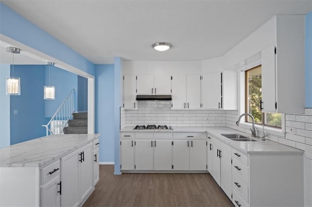 kitchen with sink, stainless steel gas cooktop, decorative light fixtures, white cabinets, and hardwood / wood-style flooring