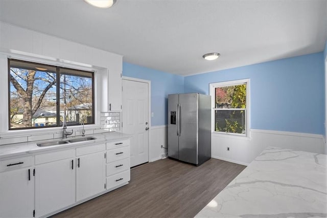 kitchen with light stone countertops, stainless steel fridge, sink, white cabinets, and dark hardwood / wood-style floors