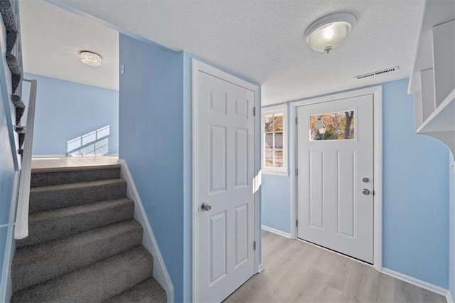 foyer with a textured ceiling and light wood-type flooring